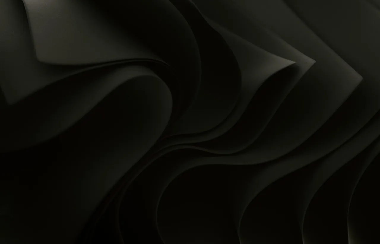Dark charcoal render of smooth overlapping wave-like sheets folding over one another in soft shadow