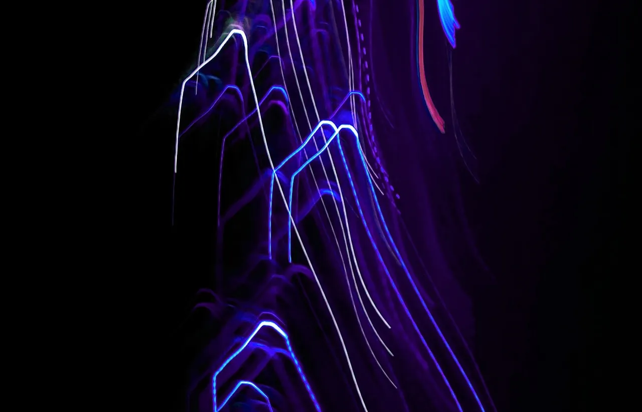 Long exposure of blue and violet light trails arcing across a black background