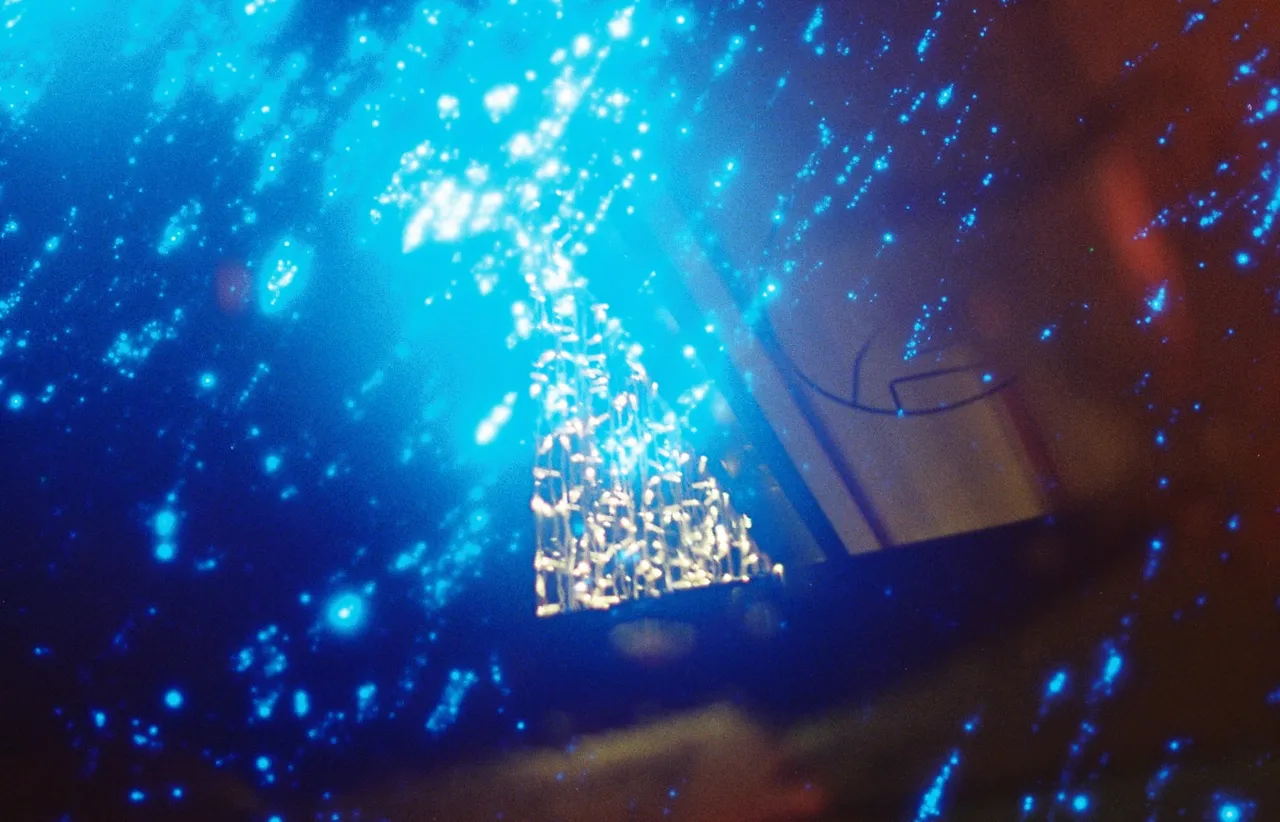 Dense blue field of scattered light particles drawing together into one bright cluster