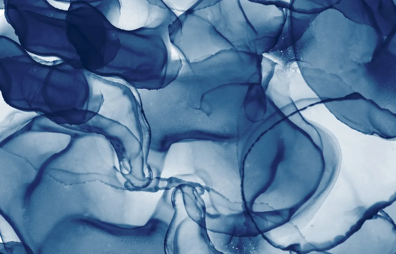 A single plume of blue ink unfurling through clear water against a dark ground