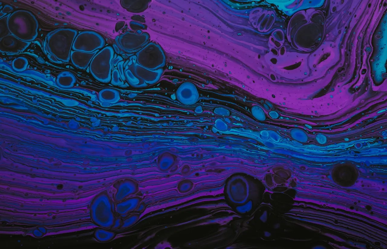 Violet and blue pigment blooming through water in soft abstract clouds