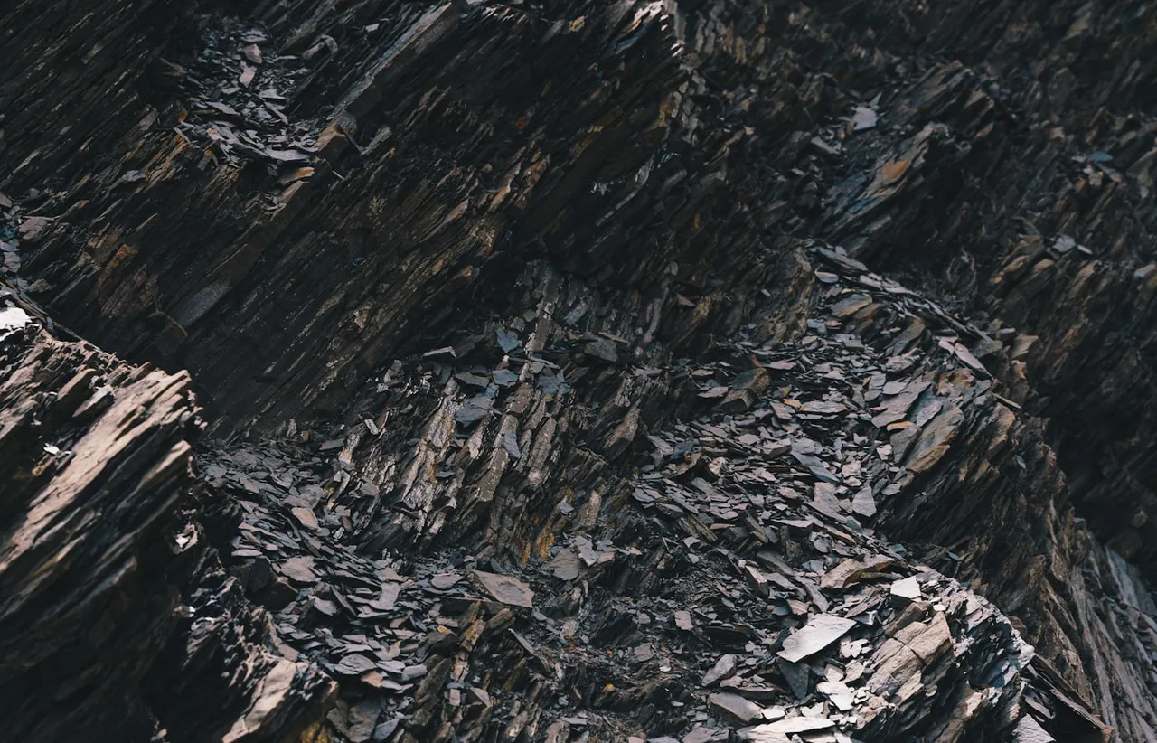 Close view of a dark slate rock face broken into angular stacked layers