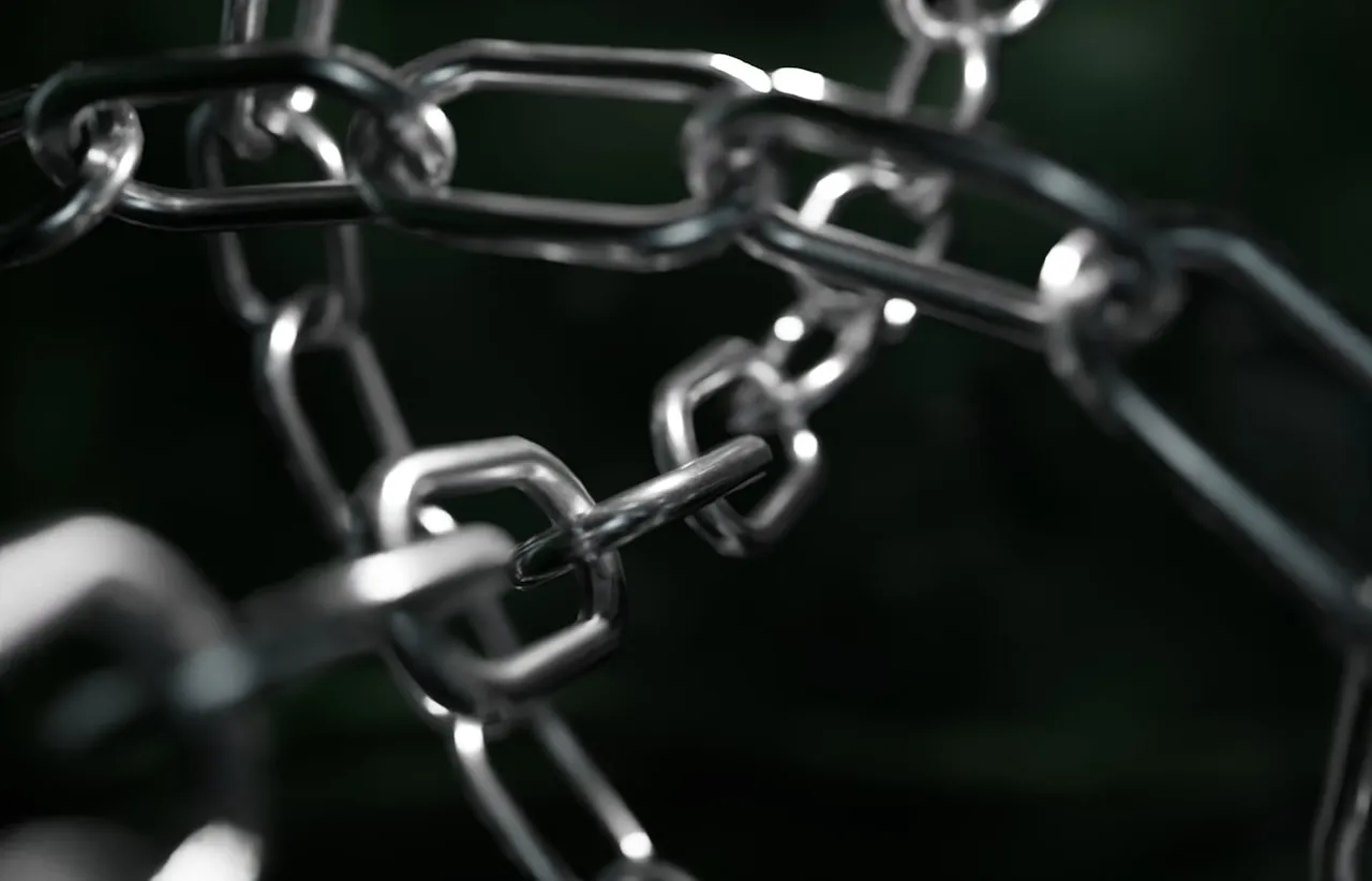 Macro photograph of polished steel chain links running in repeating interlocked rows against a dark blurred background