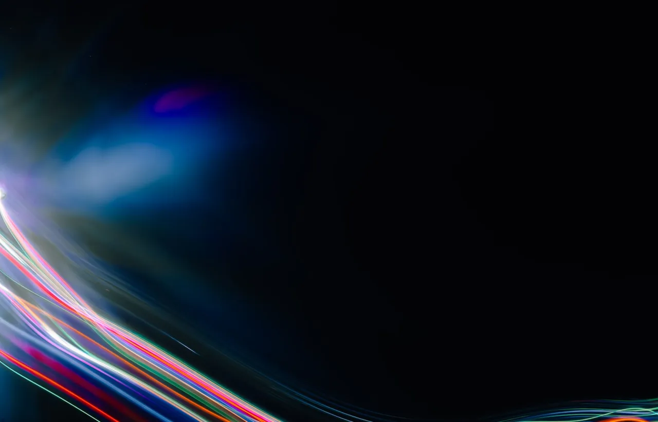 Bright purple and blue light painting trails curving across a near black frame