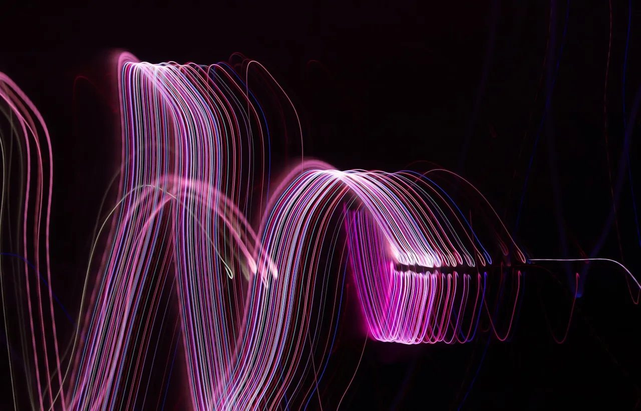 Long exposure photograph of blurred luminous light streaks trailing through darkness